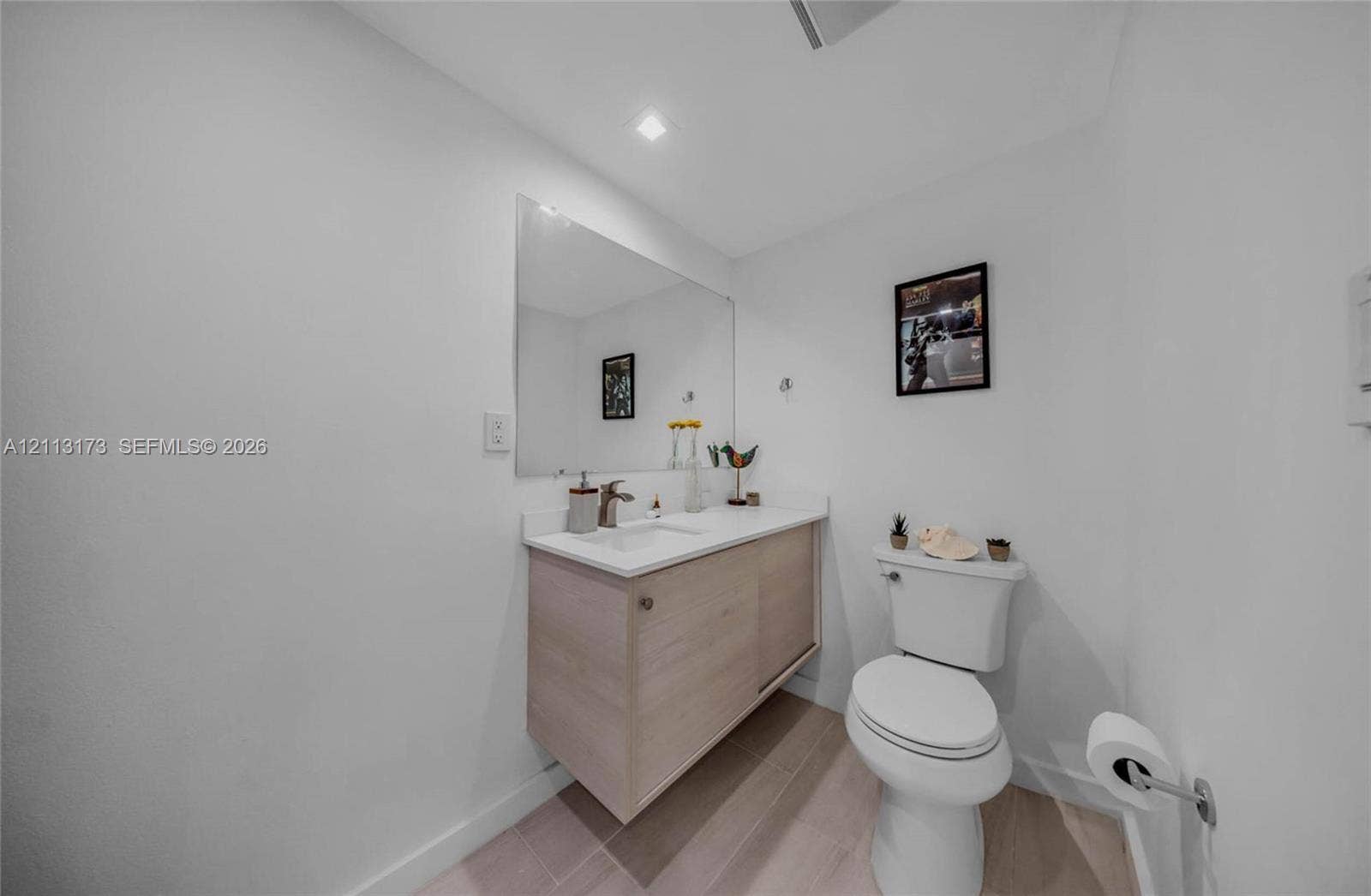 300 Bayview Drive, #1614, Sunny Isles Beach, FL 33160 Floating vanity with a light wood finish, integrated white countertop with basin, wall-mounted mirror, recessed ceiling lighting, and neutral-toned flooring
