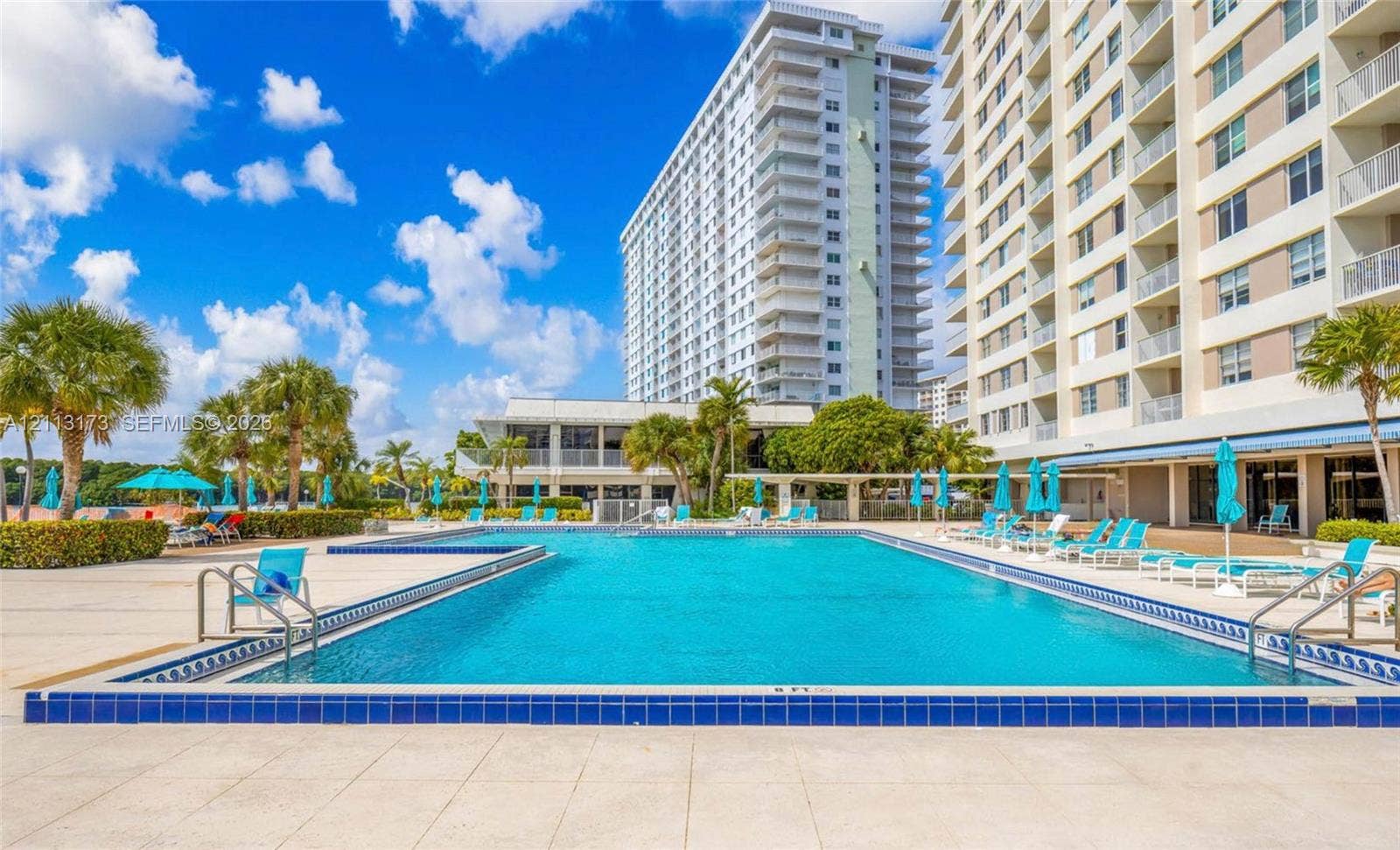 300 Bayview Drive, #1614, Sunny Isles Beach, FL 33160 Rectangular swimming pool featuring a decorative tiled border and paved deck surroundings with mature palm trees