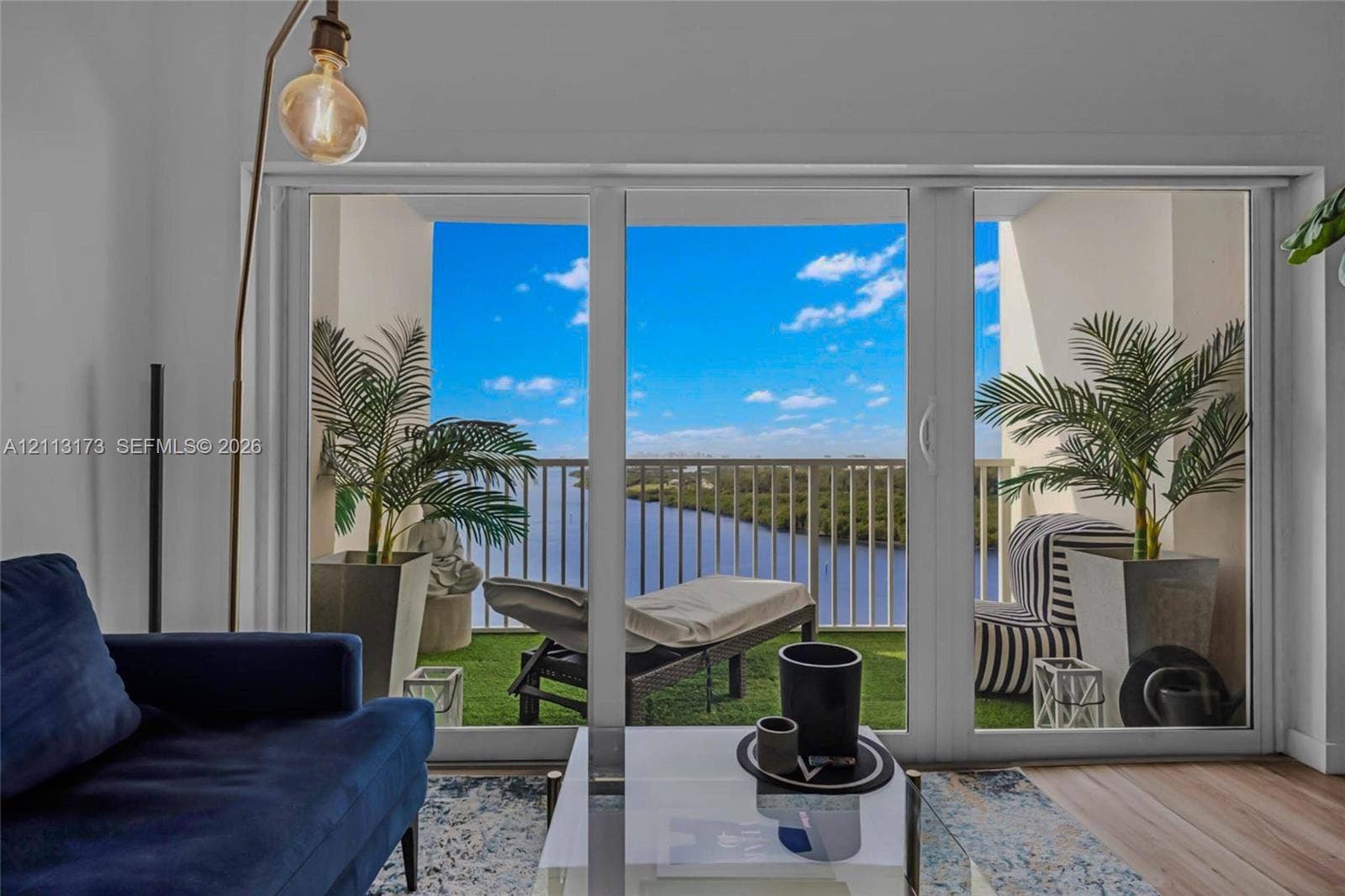 300 Bayview Drive, #1614, Sunny Isles Beach, FL 33160 Large-format glass sliding doors opening to a private balcony with metal railing, synthetic turf flooring, and water scenery