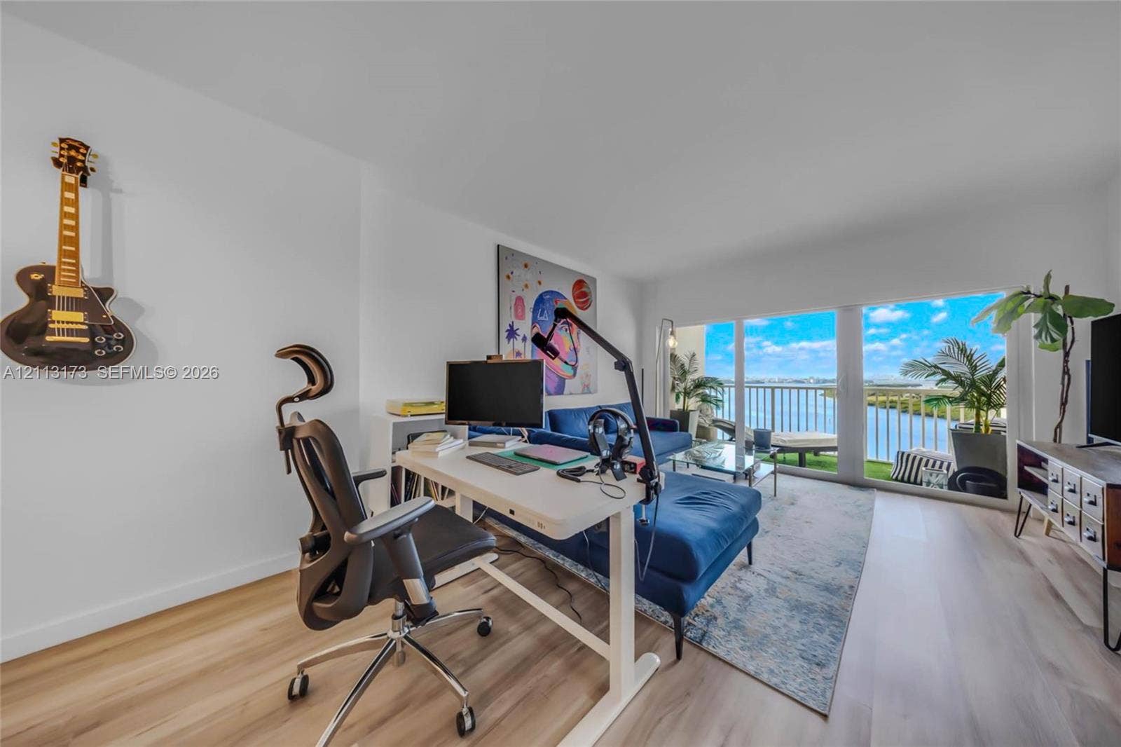 300 Bayview Drive, #1614, Sunny Isles Beach, FL 33160 Light-filled living area featuring wood-finish flooring and floor-to-ceiling glass doors opening to a balcony with waterfront scenery