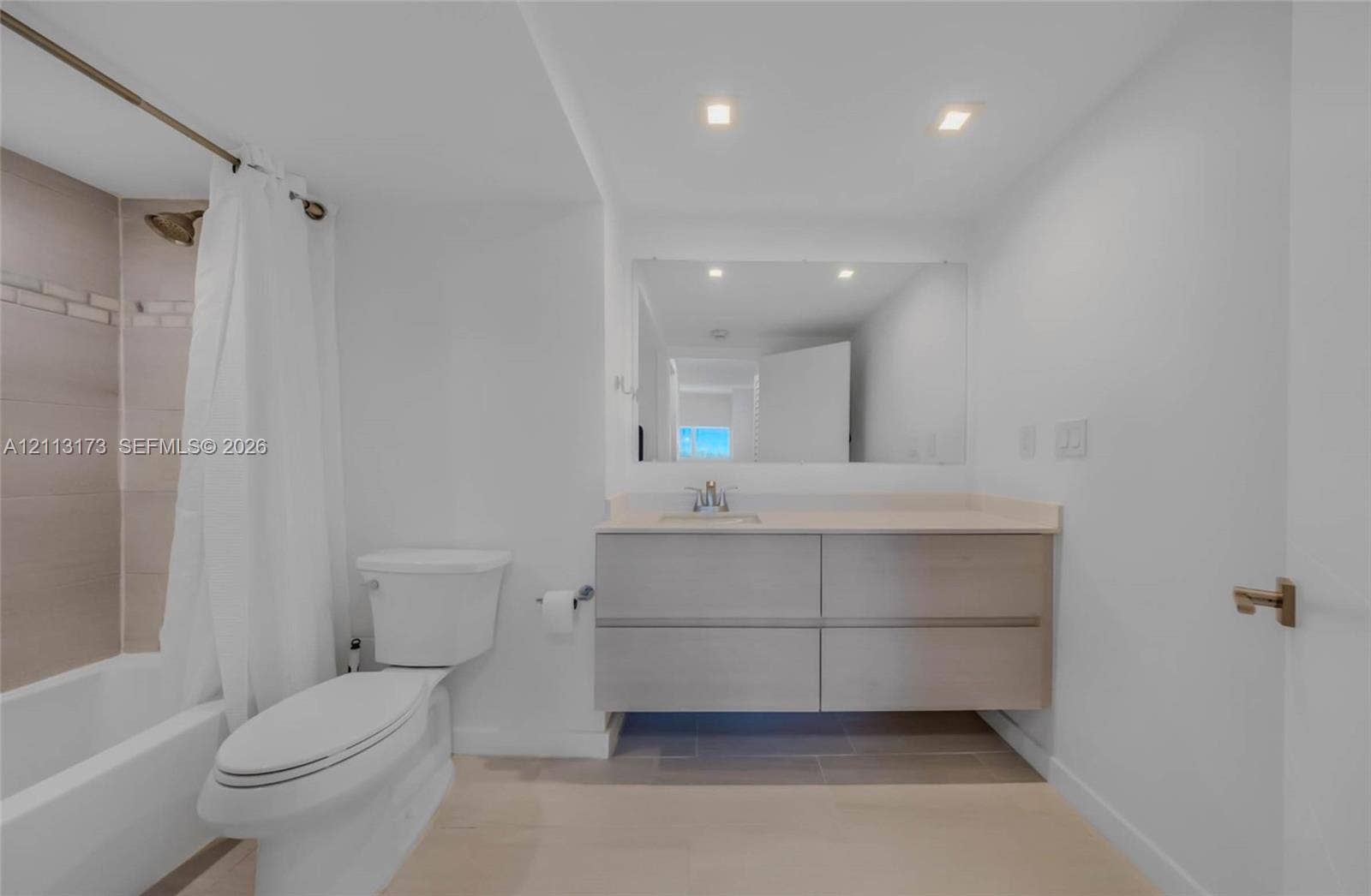 300 Bayview Drive, #1614, Sunny Isles Beach, FL 33160 Floating vanity featuring a solid surface countertop, rectangular undermount sink, large wall-mounted mirror, recessed ceiling lighting, and tile shower surround