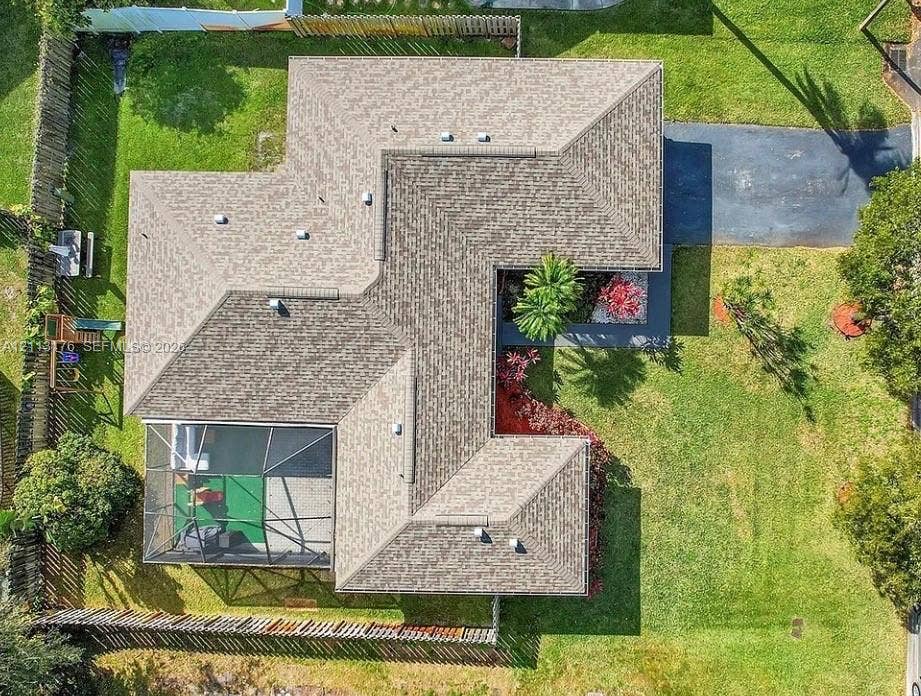 4391 NW 112th Avenue, Coral Springs, FL 33065 Aerial view featuring a multi-faceted shingle roof, an enclosed screened lanai, a paved driveway, and perimeter wood fencing surrounding the lot
