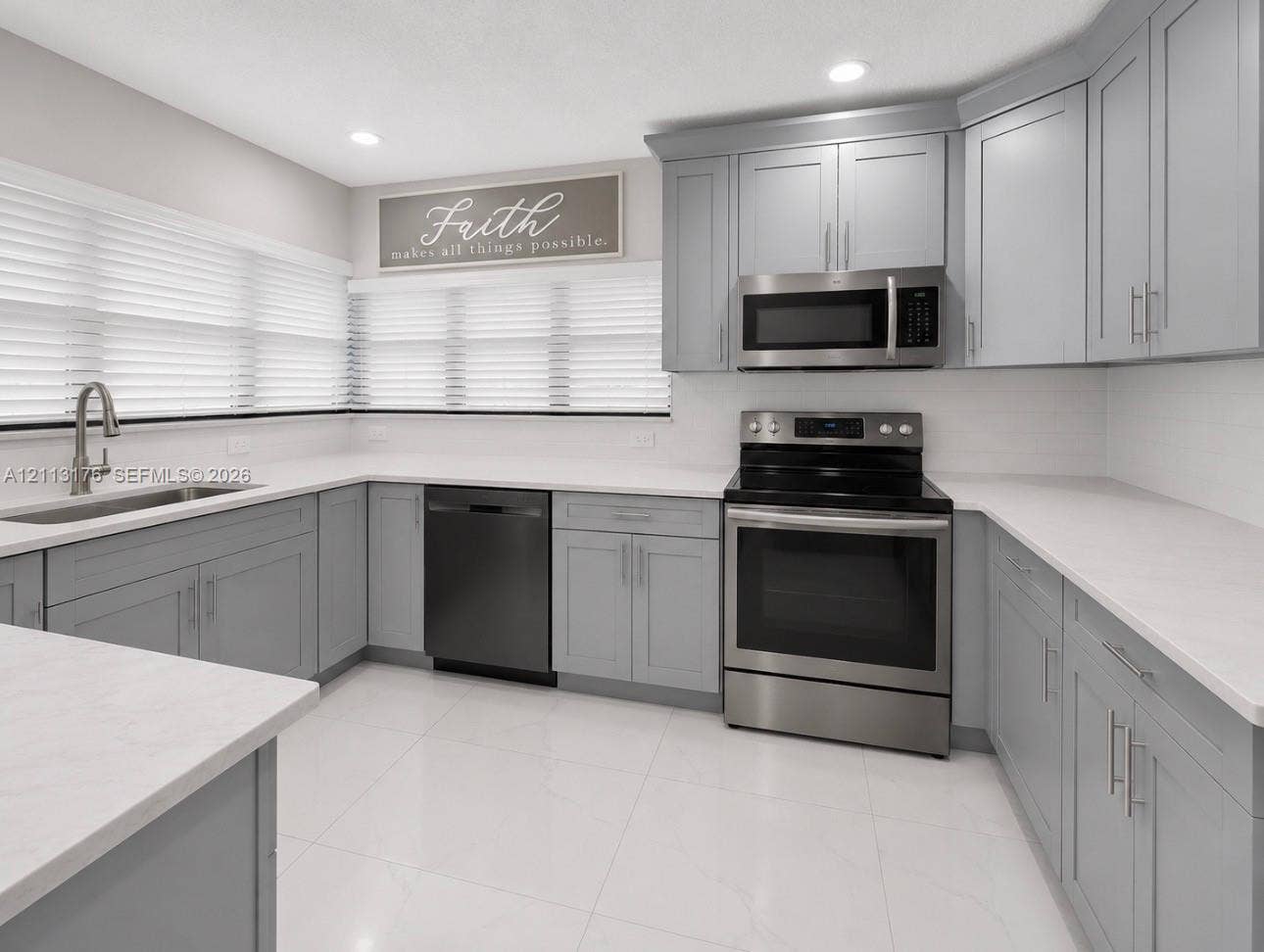 4391 NW 112th Avenue, Coral Springs, FL 33065 Kitchen featuring light gray shaker cabinetry, white solid-surface countertops, stainless steel appliances, and large-format tile flooring
