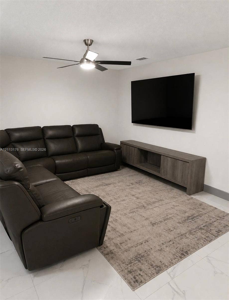 4391 NW 112th Avenue, Coral Springs, FL 33065 Neutral-toned room featuring large-format tile flooring and a brushed metal ceiling fan with integrated lighting