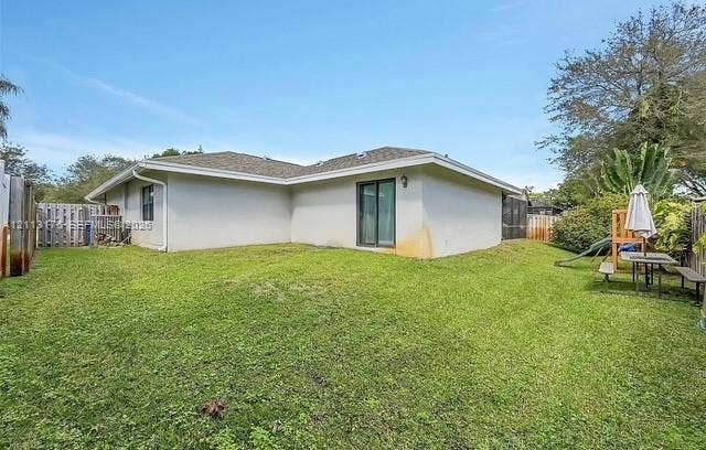 4391 NW 112th Avenue, Coral Springs, FL 33065 Stucco exterior featuring a hipped roof, glass sliding door, and enclosed backyard with wood-style fencing