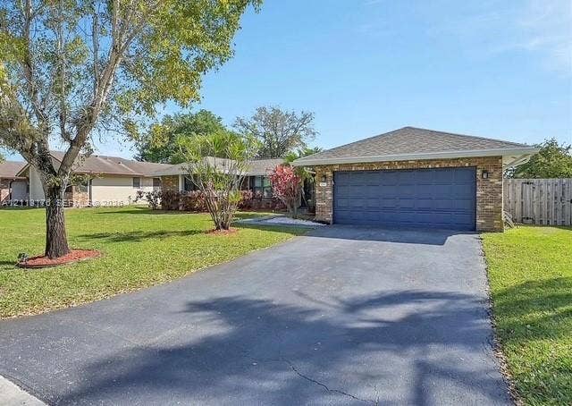 4391 NW 112th Avenue, Coral Springs, FL 33065 Stone veneer facade featuring a two-car garage, asphalt driveway, and manicured landscaping