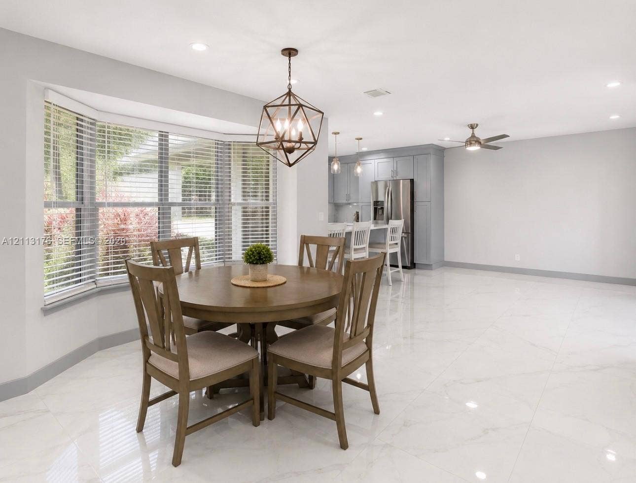 4391 NW 112th Avenue, Coral Springs, FL 33065 Open-concept space featuring polished stone-look tile flooring, bay window with slatted blinds, geometric pendant lighting, and recessed ceiling lights