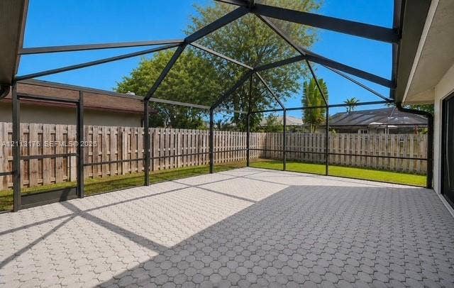 4391 NW 112th Avenue, Coral Springs, FL 33065 Screened-in patio featuring a paved floor, metal frame, and wood fencing
