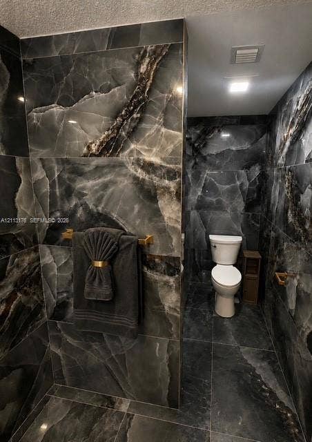 4391 NW 112th Avenue, Coral Springs, FL 33065 Full-height charcoal stone-finish wall tile with high-contrast veining, integrated recessed lighting, and brushed gold-tone hardware fixtures