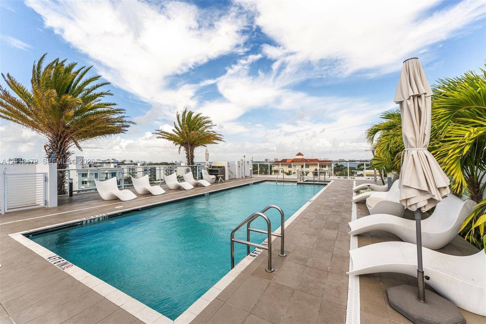 1150 102nd Street, #703, Bay Harbor Islands, FL 33154 Rooftop swimming pool featuring tile decking, stainless steel handrails, and glass perimeter railings