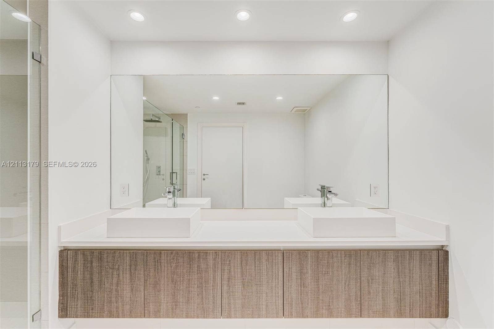 1150 102nd Street, #703, Bay Harbor Islands, FL 33154 Floating vanity with wood-finish cabinetry, dual square vessel sinks, white countertop, and large wall-to-wall mirror with recessed ceiling lighting
