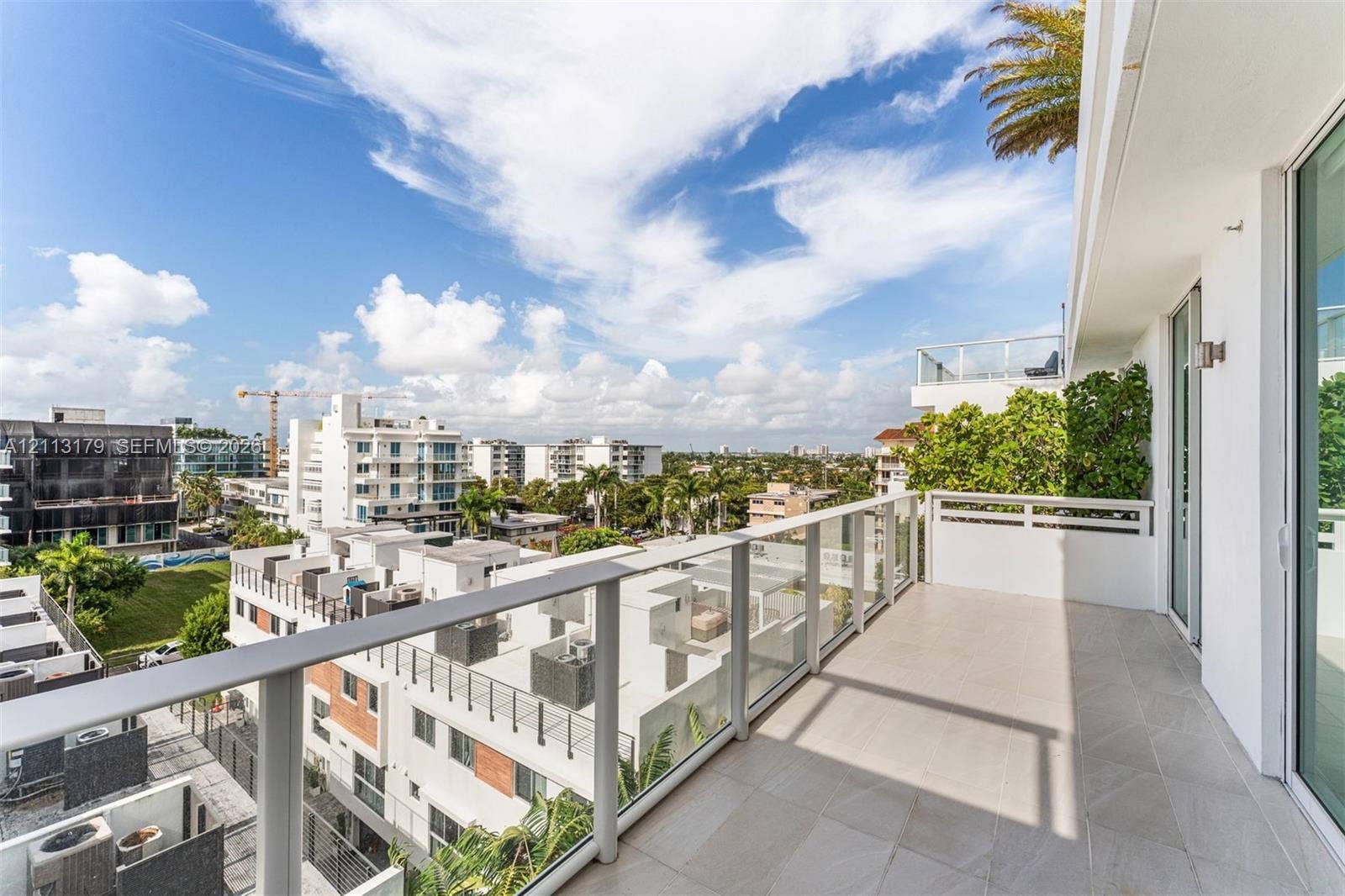 1150 102nd Street, #703, Bay Harbor Islands, FL 33154 Covered balcony featuring tile flooring and a glass-paneled railing