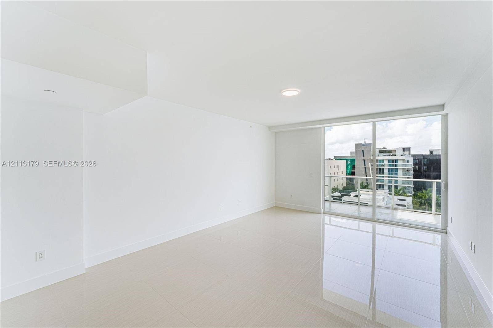 1150 102nd Street, #703, Bay Harbor Islands, FL 33154 Neutral-toned tile flooring, recessed ceiling lighting, and sliding glass doors with access to an exterior balcony
