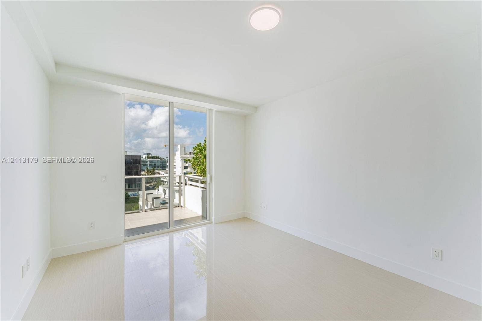 1150 102nd Street, #703, Bay Harbor Islands, FL 33154 Room featuring large-format light-toned flooring, expansive glass sliding doors, and a private balcony