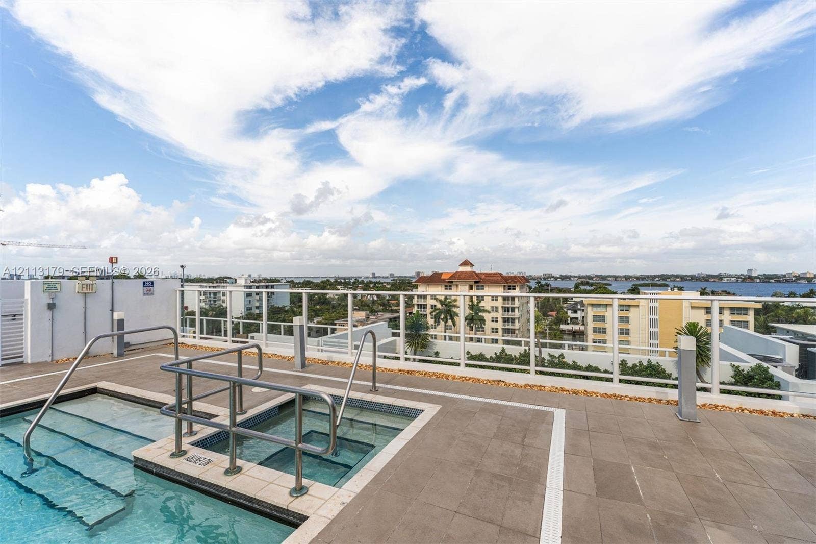 1150 102nd Street, #703, Bay Harbor Islands, FL 33154 Rooftop terrace featuring a tiled deck, integrated pool with metal safety rails, and a glass perimeter railing