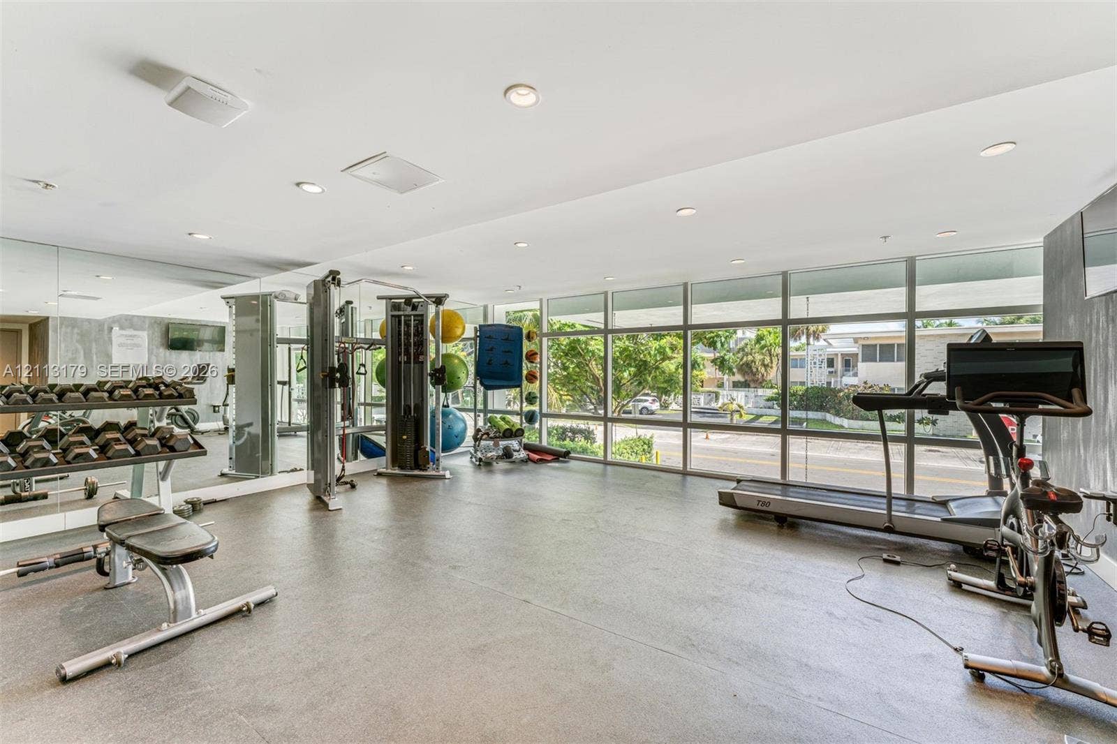 1150 102nd Street, #703, Bay Harbor Islands, FL 33154 Fitness center featuring floor-to-ceiling windows, mirrored wall panels, recessed lighting, and resilient flooring