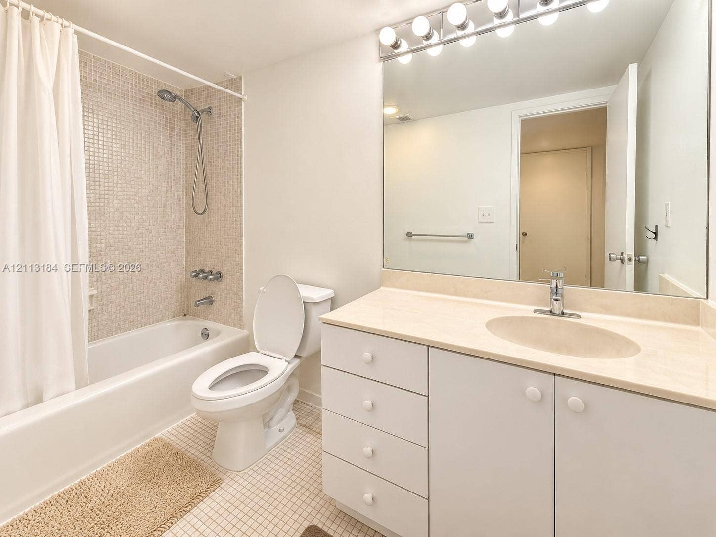 19380 Collins Avenue, #708, Sunny Isles Beach, Sunny Isles Beach, FL 33160 Bathroom featuring a vanity with integrated sink and countertop, a large wall-mounted mirror, overhead multi-bulb lighting, and a bathtub with mosaic tile surround and handheld shower fixture