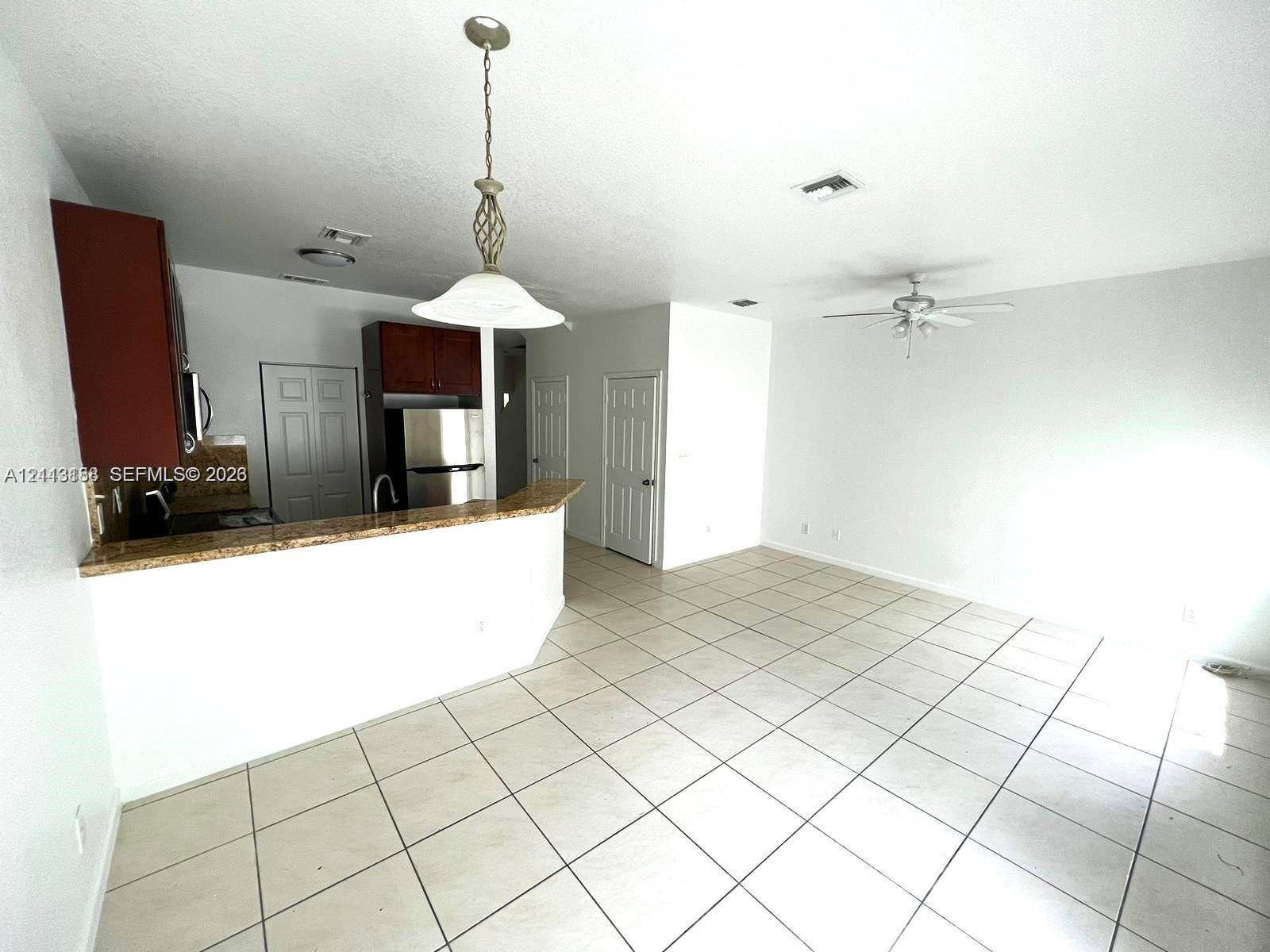 8706 NW 38th Drive, #2, Coral Springs, Coral Springs, FL 33065 Kitchen featuring stone-finish countertops, dark wood-tone cabinetry, stainless steel appliances, ceramic tile flooring, and a pendant light fixture