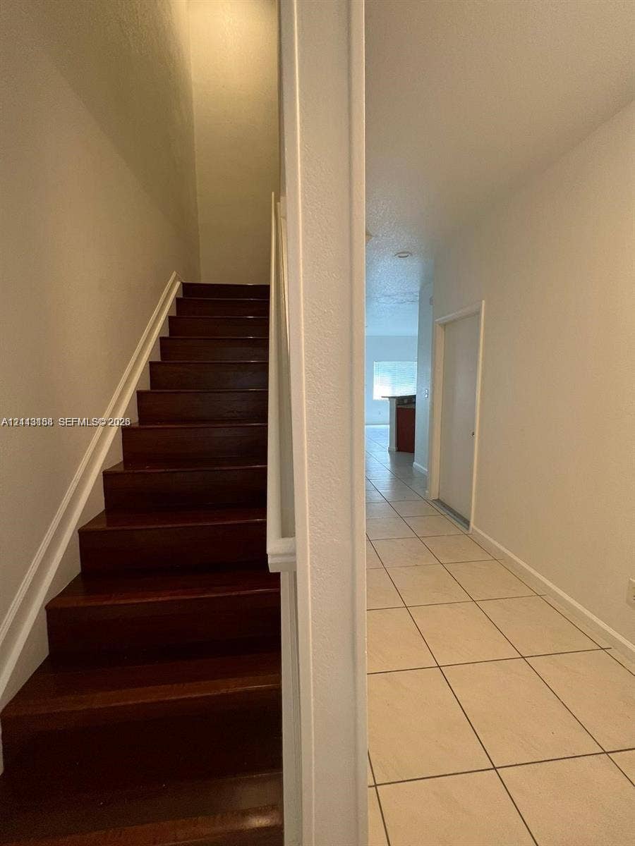 8706 NW 38th Drive, #2, Coral Springs, Coral Springs, FL 33065 Staircase featuring wood-finish treads and white railing, paired with large-format ceramic tile flooring