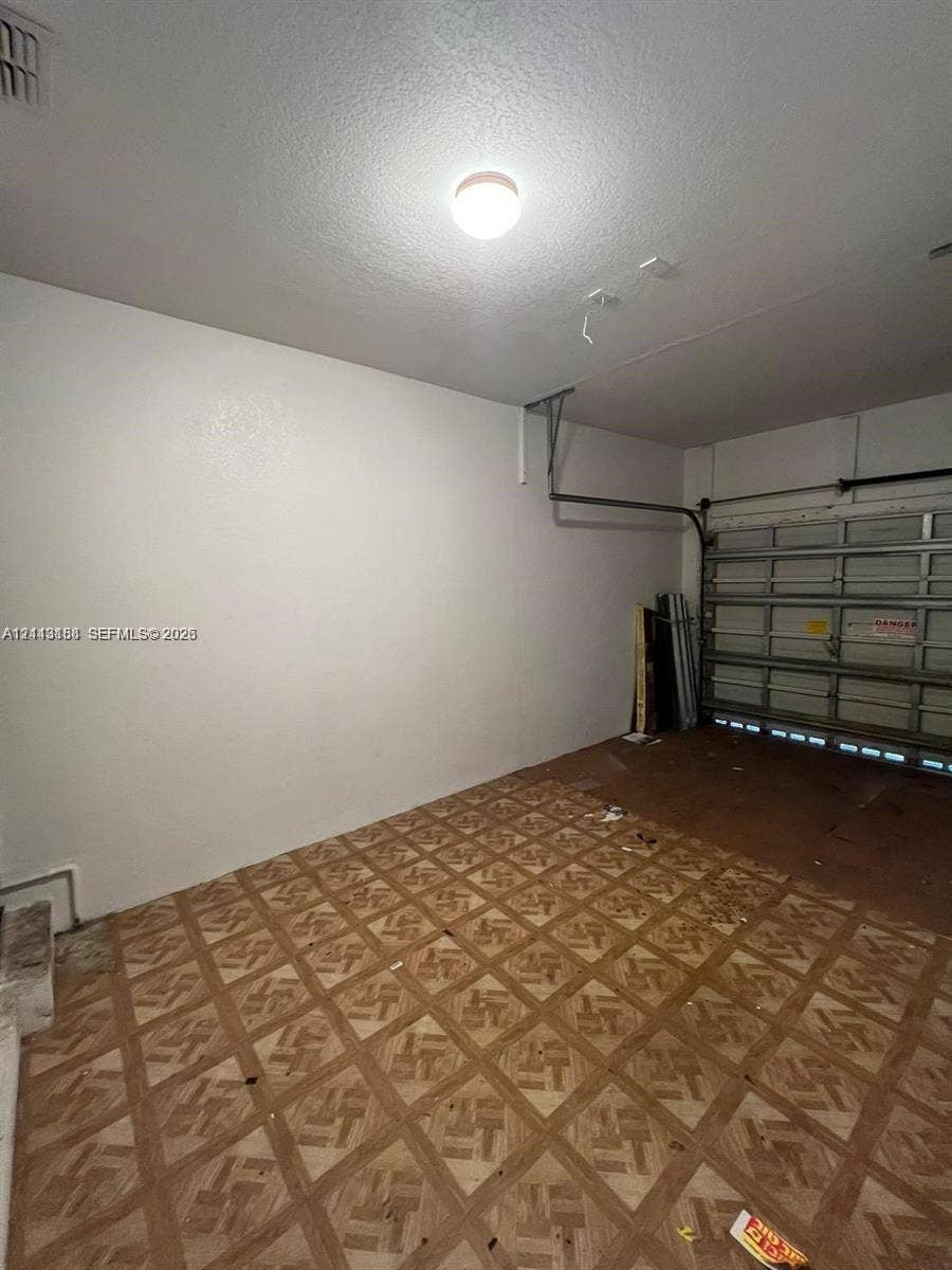 8706 NW 38th Drive, #2, Coral Springs, Coral Springs, FL 33065 Garage space featuring patterned flooring, smooth wall finishes, and a sectional overhead door