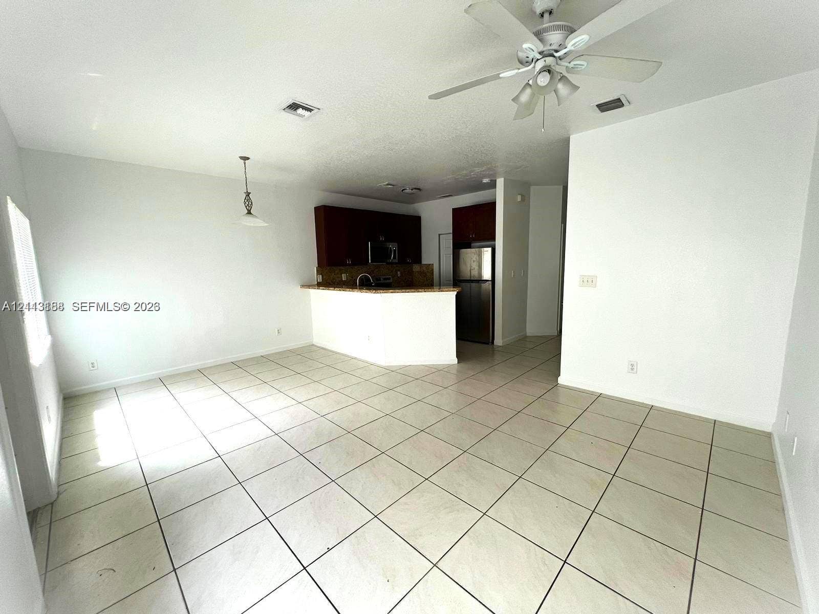 8706 NW 38th Drive, #2, Coral Springs, Coral Springs, FL 33065 Kitchen featuring a breakfast bar, dark-finish cabinetry, stainless steel refrigerator, and ceramic tile flooring throughout