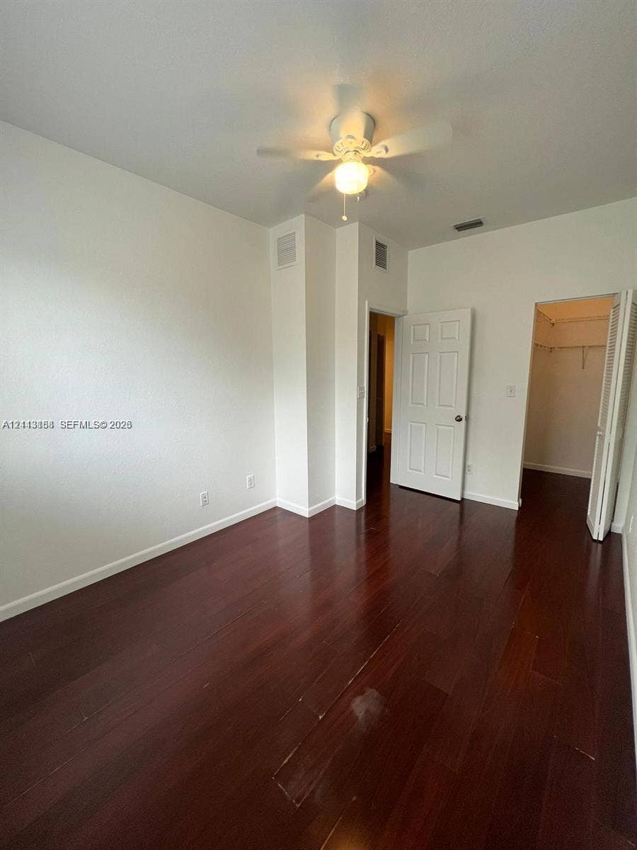 8706 NW 38th Drive, #2, Coral Springs, Coral Springs, FL 33065 Room featuring wood-finish flooring, a white ceiling fan with integrated lighting, and a walk-in closet with built-in shelving