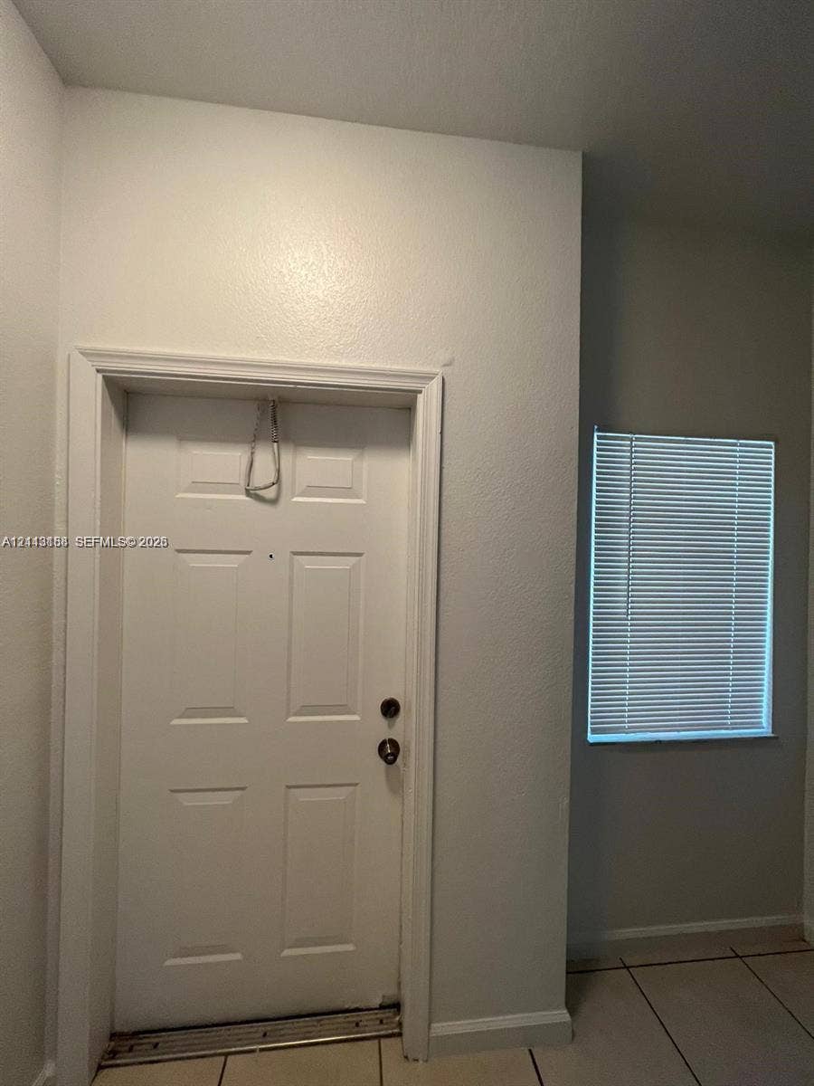 8706 NW 38th Drive, #2, Coral Springs, Coral Springs, FL 33065 Six-panel door with metallic hardware, recessed peephole, and neutral-toned ceramic tile flooring