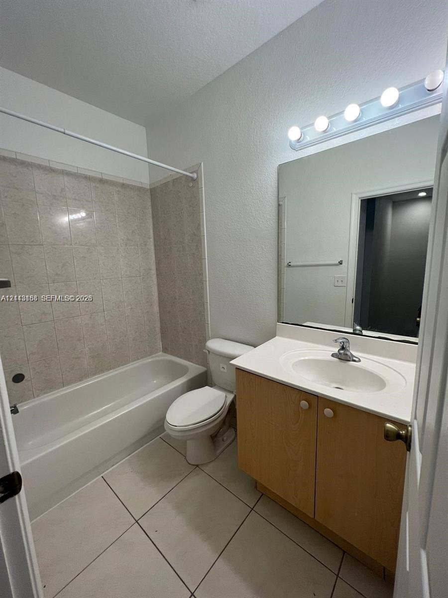8706 NW 38th Drive, #2, Coral Springs, Coral Springs, FL 33065 Full bathroom featuring a vanity with integrated sink, large wall-mounted mirror, multi-bulb vanity light, and a tub with tiled surround