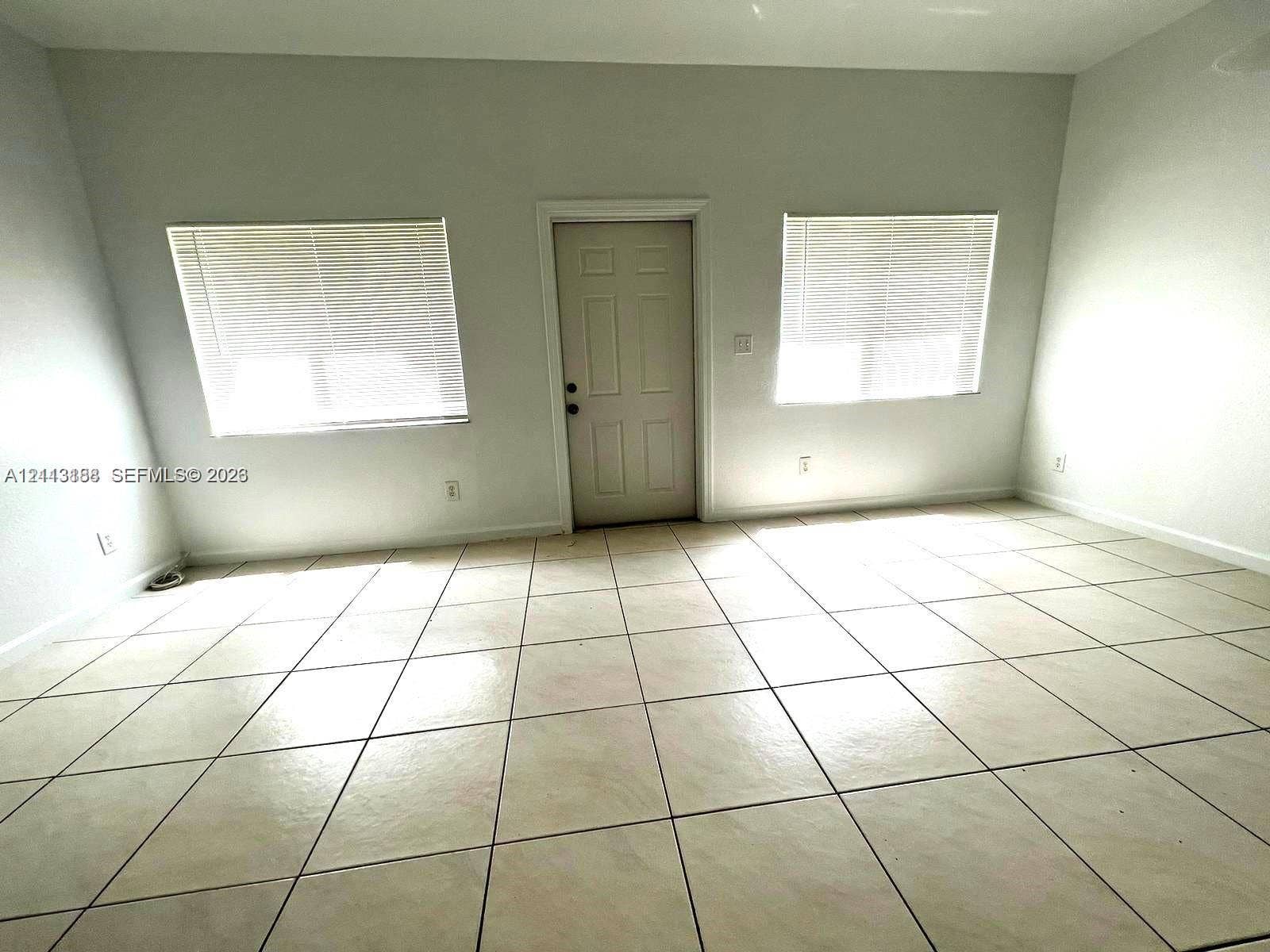 8706 NW 38th Drive, #2, Coral Springs, Coral Springs, FL 33065 Interior space featuring large-format ceramic tile flooring, neutral wall tones, two dual-pane windows, and a central solid-panel entry door