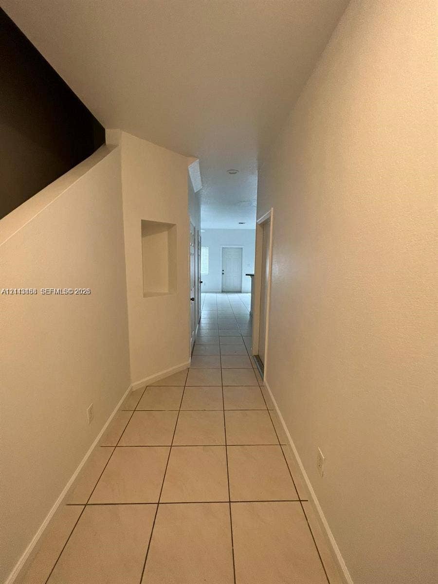 8706 NW 38th Drive, #2, Coral Springs, Coral Springs, FL 33065 Hallway featuring neutral-tone tile flooring, built-in recessed wall niche, and smooth-finish walls
