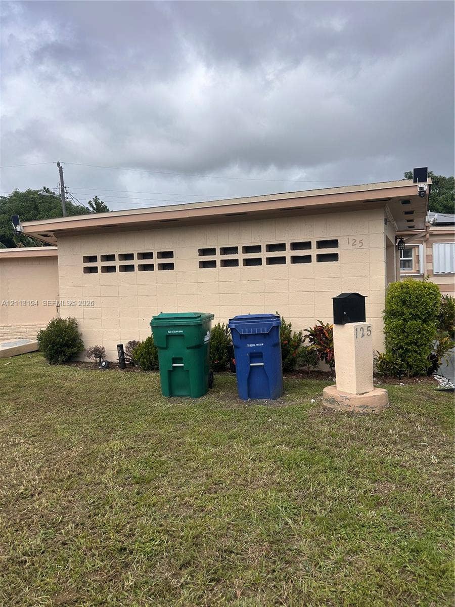 Concrete block exterior featuring decorative horizontal vents and a ground-mounted pedestal mailbox