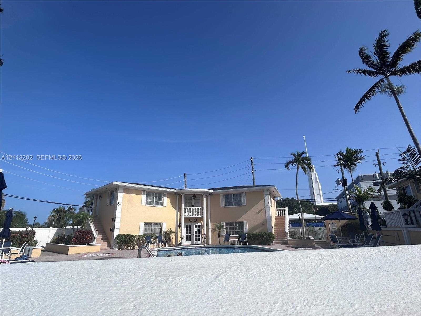 5700 NE 22nd Way, #324, Fort Lauderdale, Fort Lauderdale, FL 33308 Two-story exterior featuring a central covered entryway with columns, a balcony, exterior staircases, and a ground-level swimming pool