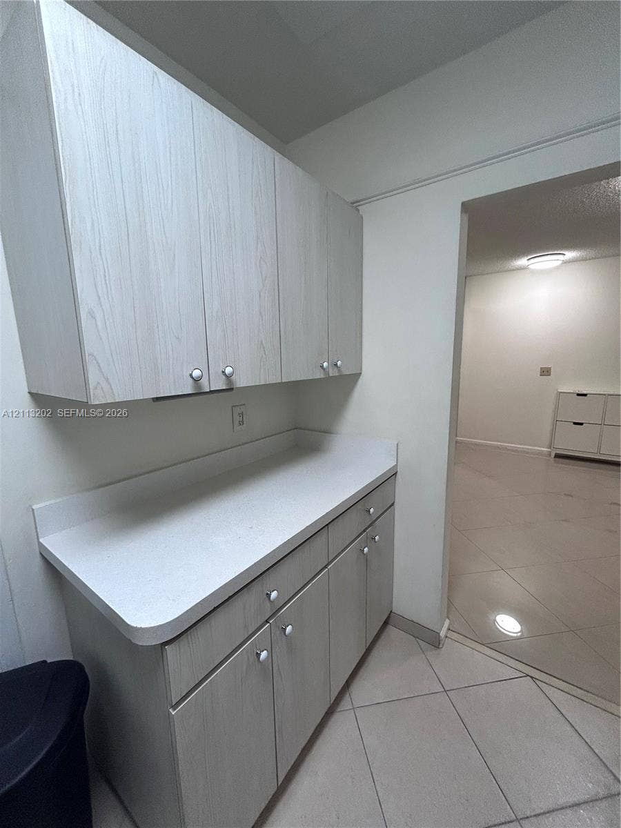 5700 NE 22nd Way, #324, Fort Lauderdale, Fort Lauderdale, FL 33308 Light wood-finish cabinetry featuring white knobs, white solid-surface countertops, and ceramic tile flooring
