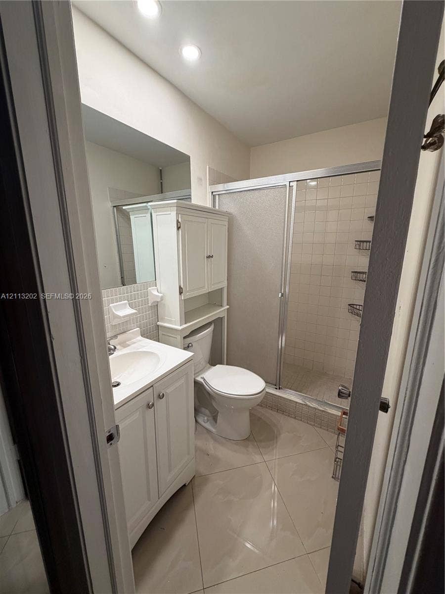 5700 NE 22nd Way, #324, Fort Lauderdale, Fort Lauderdale, FL 33308 Bathroom featuring tile flooring, a white vanity cabinet with an integrated sink, a built-in storage hutch, and a glass-enclosed shower with tiled walls