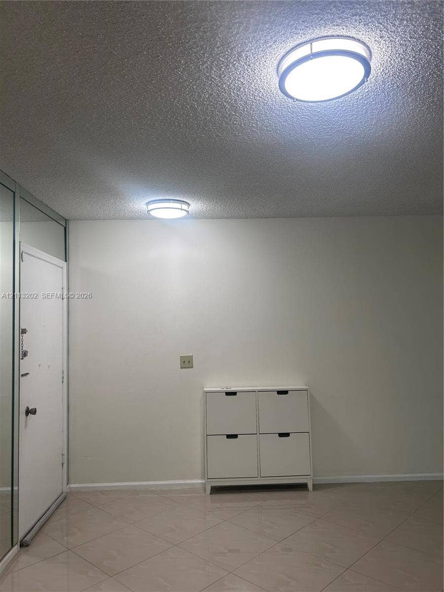 5700 NE 22nd Way, #324, Fort Lauderdale, Fort Lauderdale, FL 33308 Interior space featuring neutral wall tones, large-format tile flooring, dual round flush-mount ceiling fixtures, and mirrored wall panelling