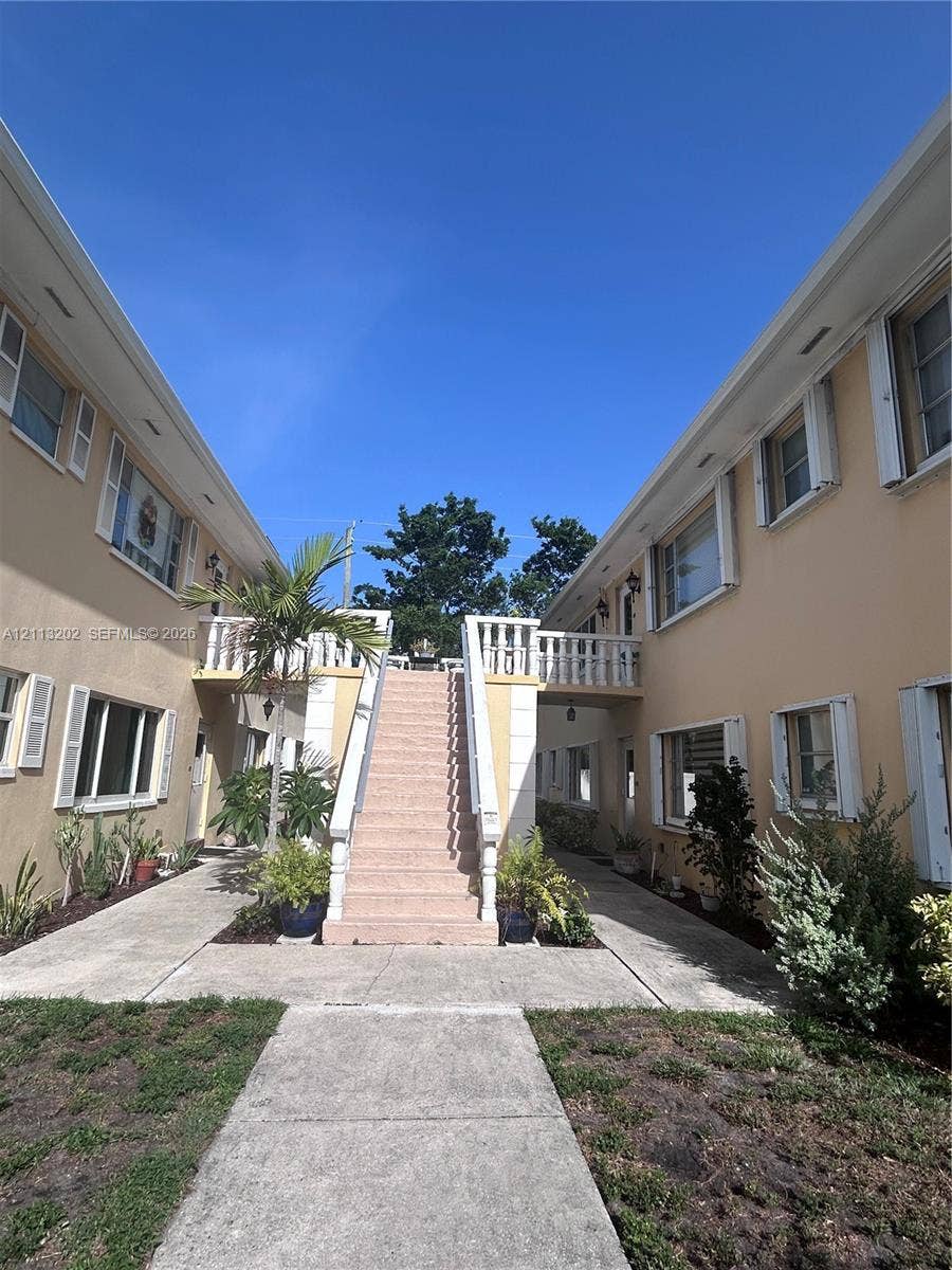 5700 NE 22nd Way, #324, Fort Lauderdale, Fort Lauderdale, FL 33308 Stucco exterior featuring a central stone staircase, balustrade railings, shuttered windows, and concrete walkways