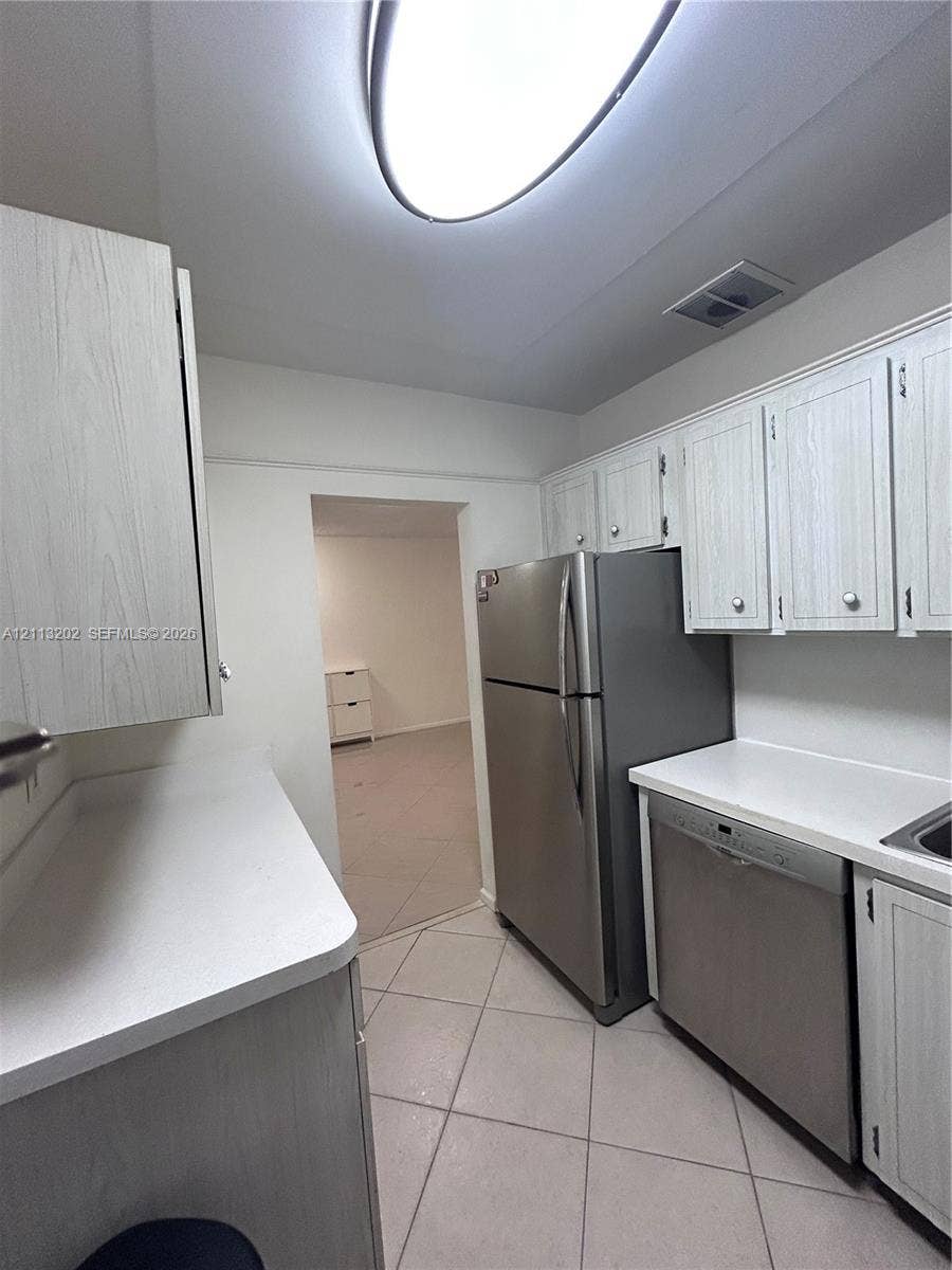 5700 NE 22nd Way, #324, Fort Lauderdale, Fort Lauderdale, FL 33308 Kitchen featuring wood-grain cabinetry, solid surface countertops, stainless steel refrigerator, stainless steel dishwasher, and tile flooring