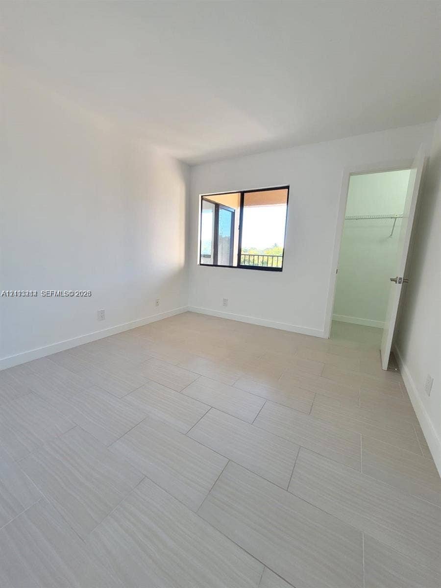 Neutral-toned tile flooring, light-filled interior, horizontal sliding window, and walk-in closet with built-in shelving