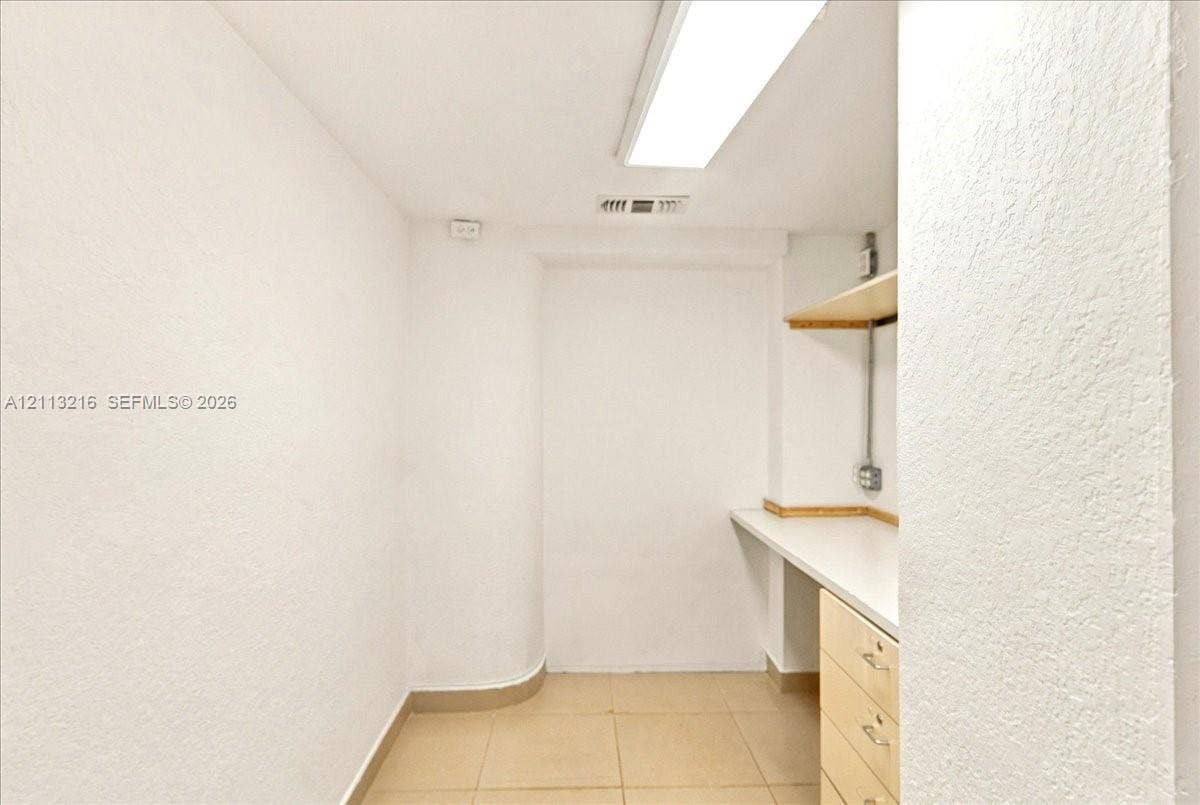 900 Bay Drive, #425, Miami Beach, FL 33141 Neutral workspace featuring ceramic tile flooring, built-in cabinetry with a white countertop, and wall-mounted shelving