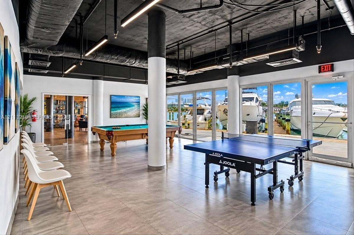 900 Bay Drive, #425, Miami Beach, FL 33141 Industrial-style recreational space featuring floor-to-ceiling glass panel walls, exposed black ceilings, structural columns, and large-format tile flooring