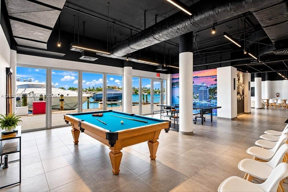 900 Bay Drive, #425, Miami Beach, FL 33141 Industrial-style common area featuring floor-to-ceiling windows, porcelain tile flooring, exposed ductwork, cylindrical support columns, and marina frontage