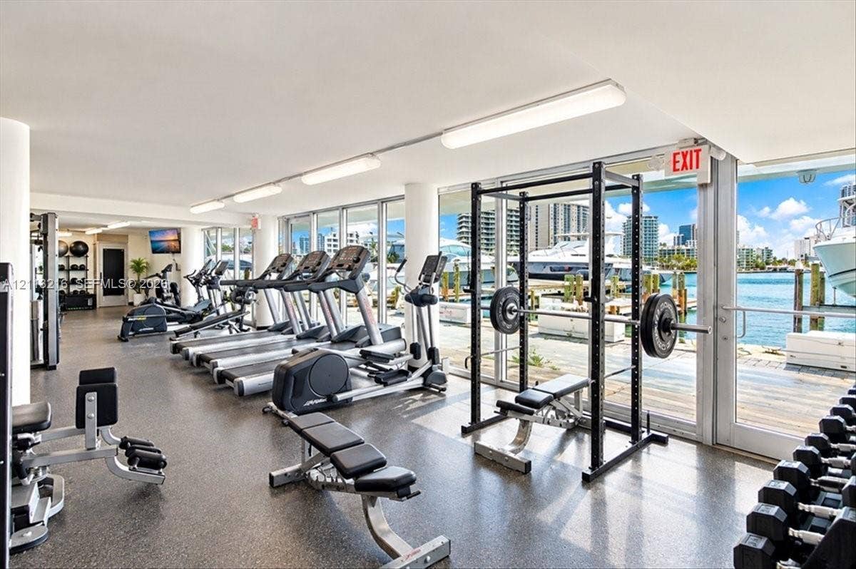 900 Bay Drive, #425, Miami Beach, FL 33141 Fitness center featuring floor-to-ceiling windows, waterfront scenery, rubberized flooring, linear lighting, and built-in structural columns