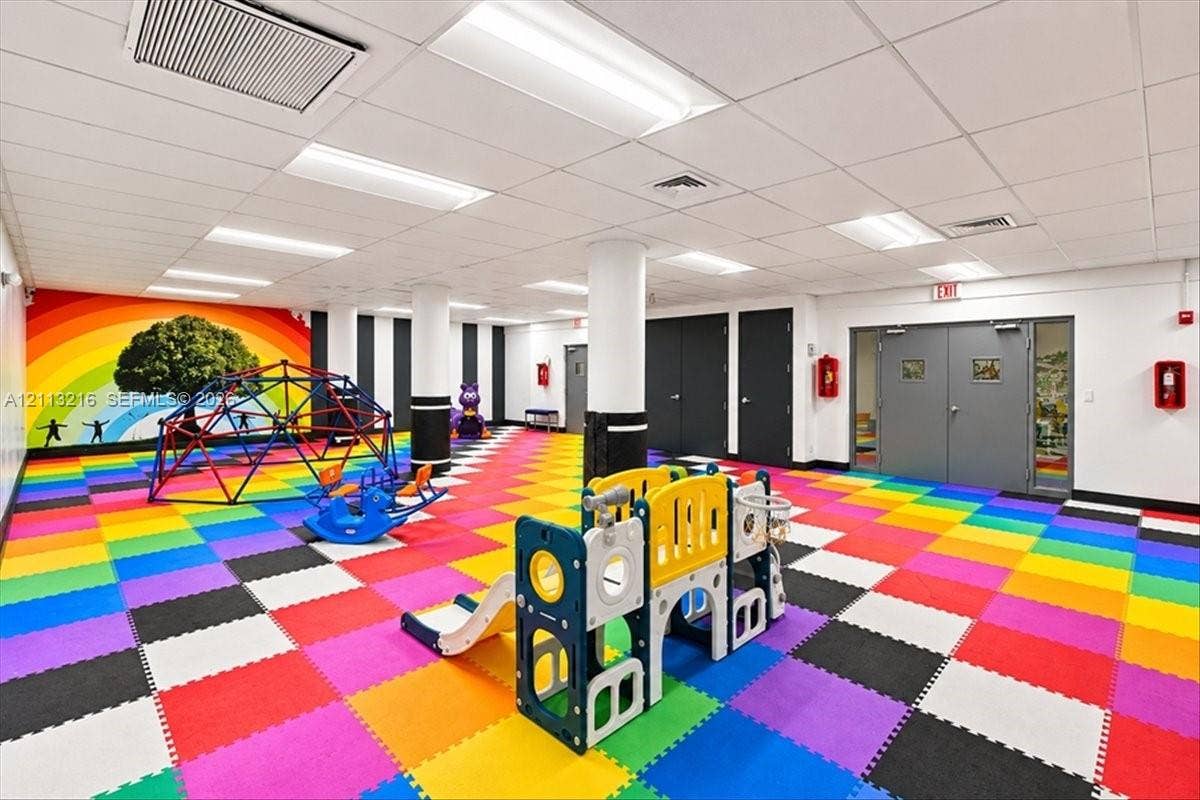 900 Bay Drive, #425, Miami Beach, FL 33141 Multi-purpose recreation room featuring modular foam tile flooring, a recessed drop ceiling, structural support columns, and double-door entry points