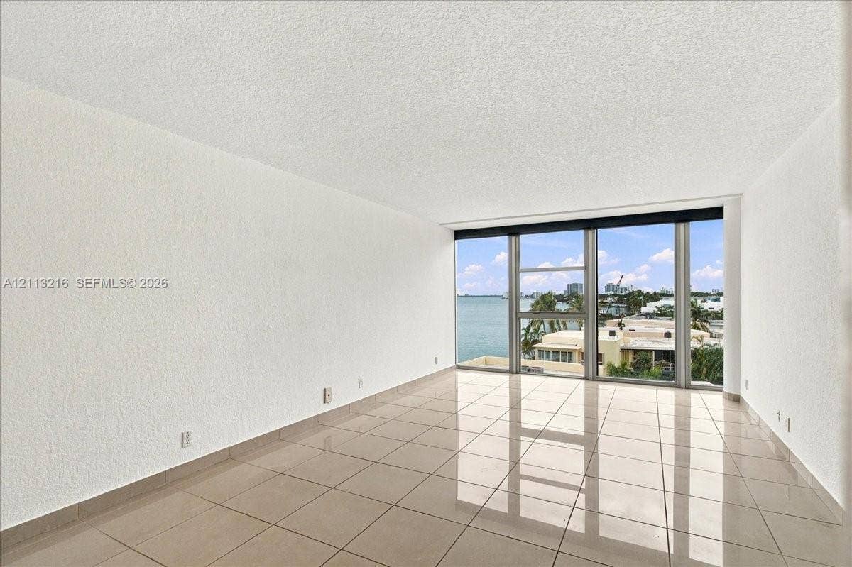 900 Bay Drive, #425, Miami Beach, FL 33141 Expansive room featuring polished tile flooring, floor-to-ceiling windows, and water scenery