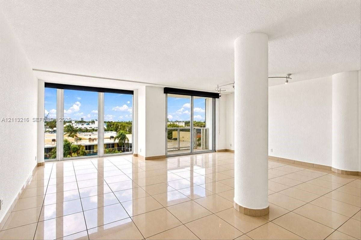 900 Bay Drive, #425, Miami Beach, FL 33141 Open-concept interior featuring large-format tile flooring, floor-to-ceiling windows, a private balcony, structural columns, and recessed track lighting