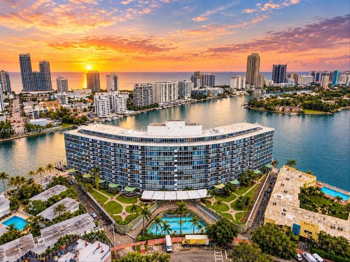 900 Bay Drive, #425, Miami Beach, FL 33141 Curved high-rise residential architecture featuring floor-to-ceiling glass paneling, a landscaped courtyard, an outdoor swimming pool, and a waterfront position