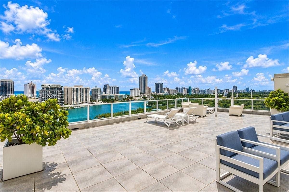 900 Bay Drive, #425, Miami Beach, FL 33141 Expansive rooftop terrace featuring large-format stone tile flooring, clear glass railings, and panoramic skyline and coastal water vistas