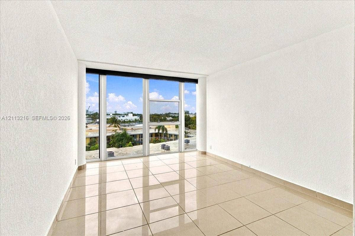 900 Bay Drive, #425, Miami Beach, FL 33141 Floor-to-ceiling windows with exterior scenery, neutral tile flooring, and smooth-finish walls