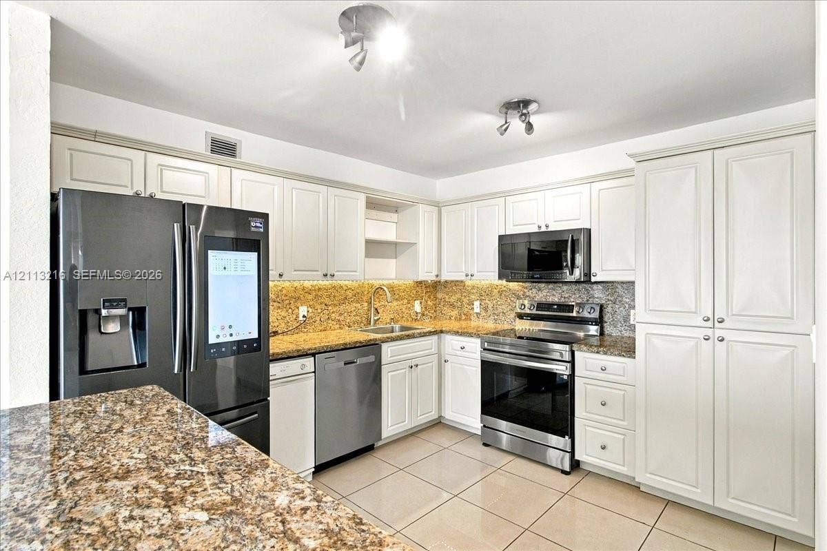 900 Bay Drive, #425, Miami Beach, FL 33141 Kitchen featuring white cabinetry, stone-finish countertops, stainless steel appliances, and tile flooring