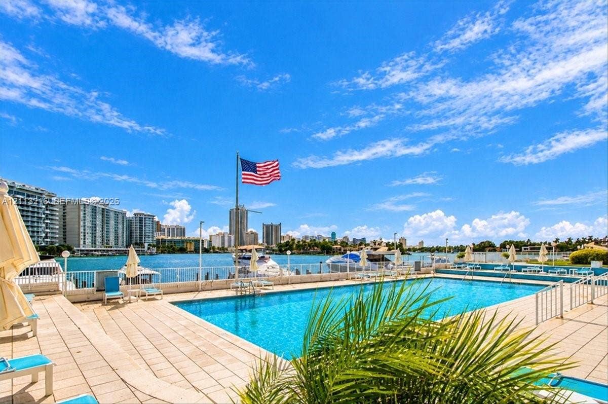 900 Bay Drive, #425, Miami Beach, FL 33141 Swimming pool featuring stone-paved decking, metal perimeter fencing, and water-front placement